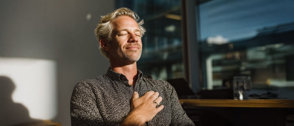 Bild av man som medvetet andas och reflekterar i ett kontorslandskap.