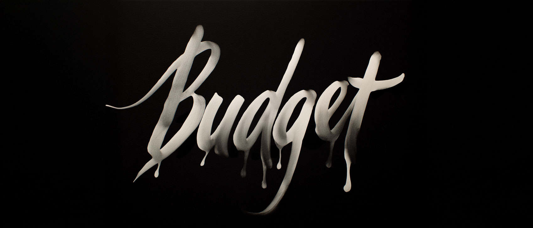Handskrivet ord "Budget" på svart bakgrund, symboliserar ekonomiska frågor.