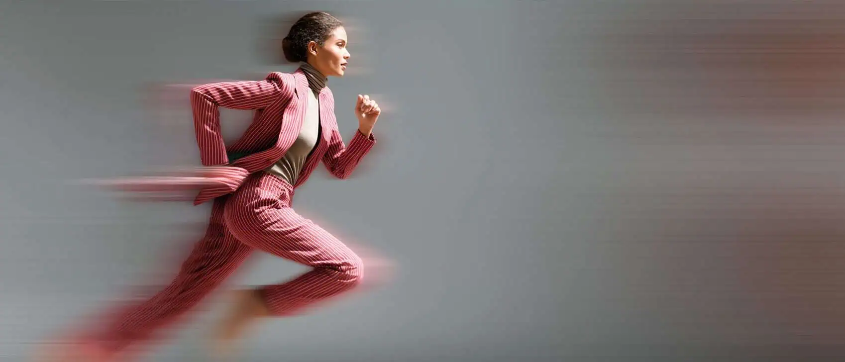 Kvinna i professionell kostym löper framåt, symboliserar snabbhet och effektivitet inom rekrytering.