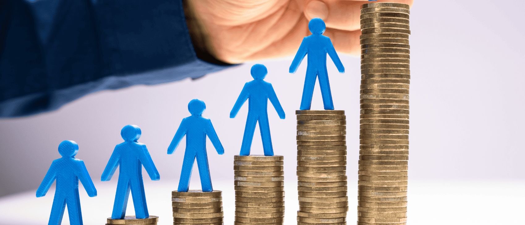 Hand som placerar små blå figurer på staplar av mynt för att visa tillväxt och rekrytering.