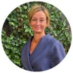 Kvinna utomhus framför grön växtvägg, leende och professionell.
